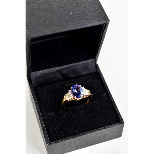 247 - An 18ct gold, diamond and tanzanite ring, the oval cut tanzanite flanked by brilliant cut and baguet... 