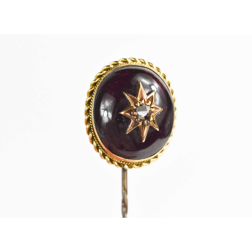 28 - A gold, garnet cabochon and old cut diamond pin, the garnet within a ropetwist border 2cm long, cent... 