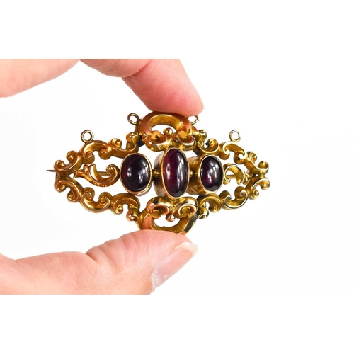 293 - A gold and garnet cabochon brooch, unmarked but testing as at least 9ct gold, composed of scrollwork... 