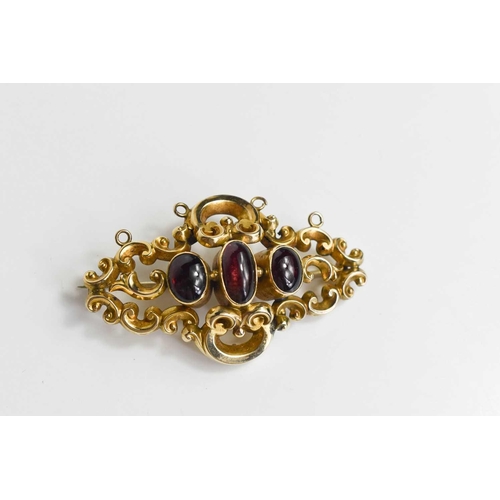 293 - A gold and garnet cabochon brooch, unmarked but testing as at least 9ct gold, composed of scrollwork... 