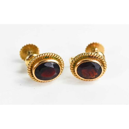 302 - A pair of 14ct gold and garnet earrings, the oval cut garnets in a ropetwist style border, with scre... 