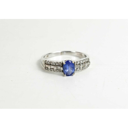 315 - An 18ct gold, tanzanite and diamond ring, the oval cut tanzanite flanked by baguette cut and brillia... 