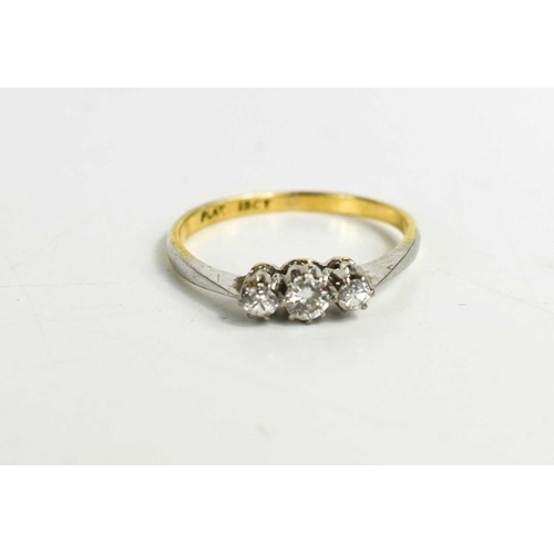 322 - An 18ct and diamond three stone ring, the brilliant cut diamonds set in a row in a claw setting, siz... 