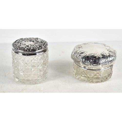 354 - Two dressing table cut glass jars with silver lids, one lid being of octagonal form with embossed fl... 