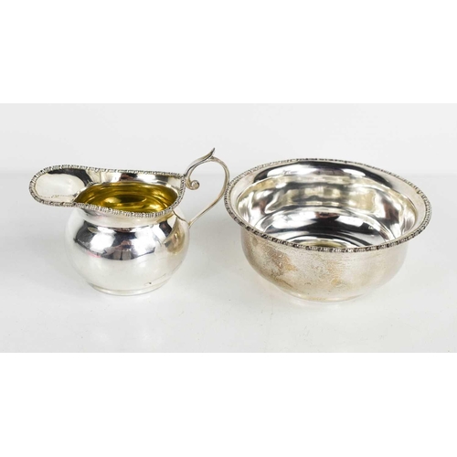 357 - A small silver cream hug of helmet form together with a small silver bowl, both hallmarked for Willi... 