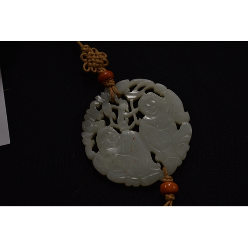 29 - A vintage Chinese pale green / white jade carved pendant, depicting two figures, 6cm diameter.