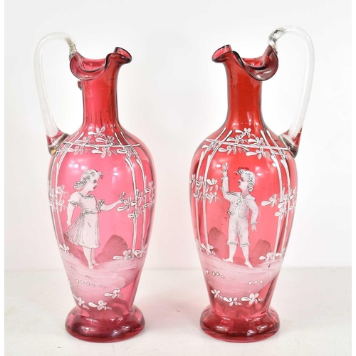 219 - A pair of Victorian Mary Gregory cranberry glass ewers, the enamel decorating depicting a young boy ... 