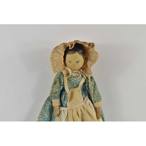 345 - An early 20th century wooden peg doll with jointed limbs and painted face, wearing a dress and bonne... 