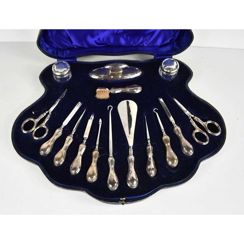 59 - A silver manicure set, comprising nail buff, two glass pots, button hooks, scissors, nail file and o... 