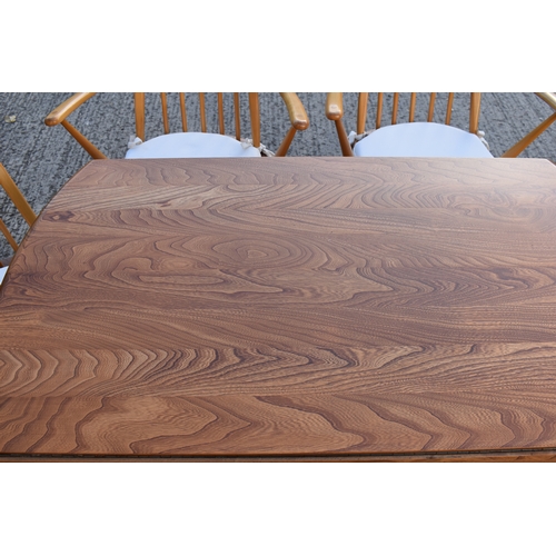 515 - An Ercol elm and beech drop leaf dining table together with four Ercol style chairs.