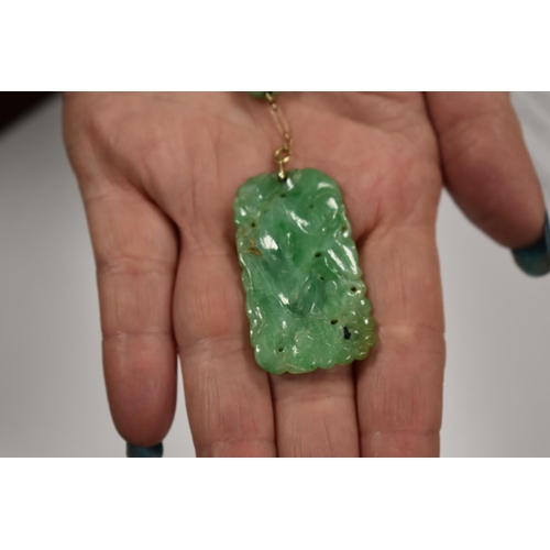 208 - A Chinese 9ct gold and jade necklace with a carved green jade pendant.