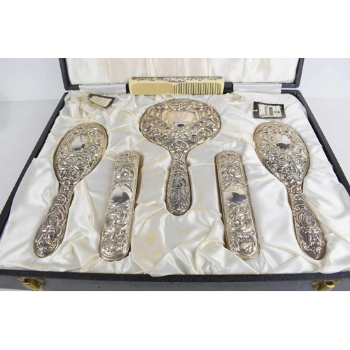 101 - A silver dressing table set, comprising hand mirror, two hair brushes, two clothes brushes and a com... 