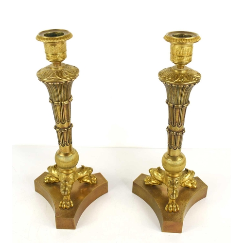 110 - A pair of Empire style gilt brass candlesticks, the candlesockets raised above a tapered column, rai... 