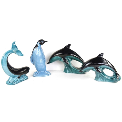 166 - A group of Poole pottery animal figures comprising of two dolphins, a penguin and a whale, 21cm high... 