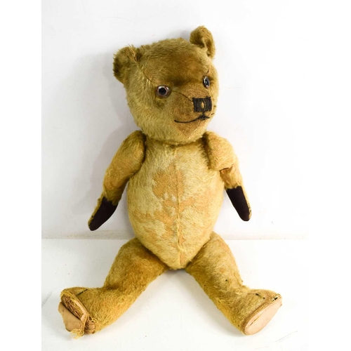 8 - A vintage teddy bear, straw filled, articulated arms and legs, 50cm long.