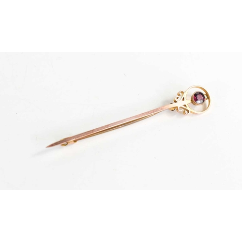 332 - A 9ct gold and ruby tie pin, the brilliant cut ruby set within a decorative roundel, 2.2g.