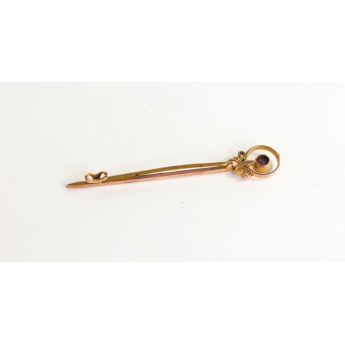 332 - A 9ct gold and ruby tie pin, the brilliant cut ruby set within a decorative roundel, 2.2g.