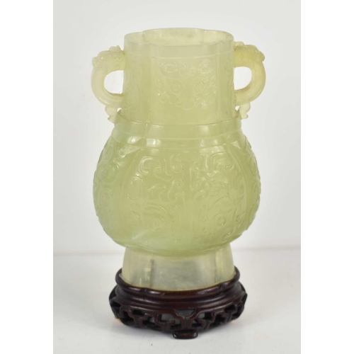 306 - A Chinese carved jade twin handled vase, decorated with stylised foliage in relief, 14cm high with s... 