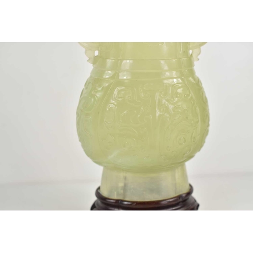 306 - A Chinese carved jade twin handled vase, decorated with stylised foliage in relief, 14cm high with s... 