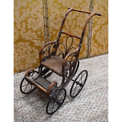 112 - A late Victorian/early Edwardian child's wooden and cane dolls push chair with foot rest, metal unde... 