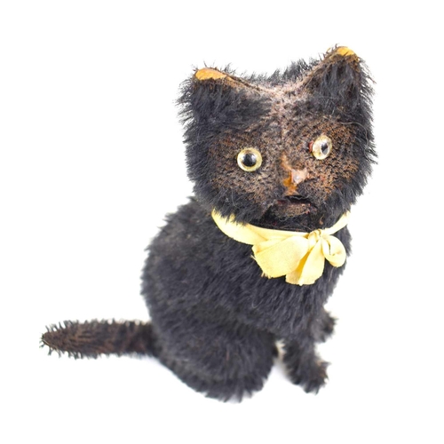 72 - A small vintage automaton black cat, with glass eyes, and cream silk bow, winding hole to the back, ... 