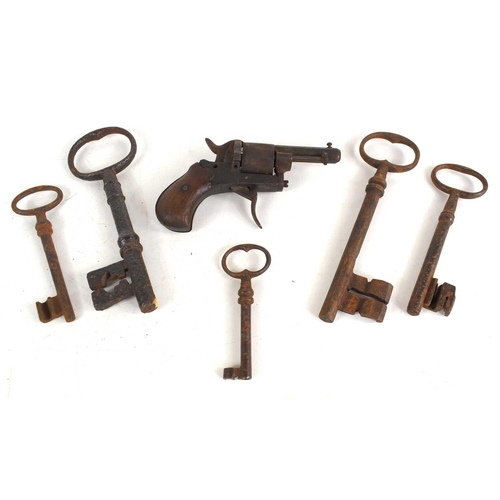 A group of antique keys, various sizes, and a vintage pin fire revolver.