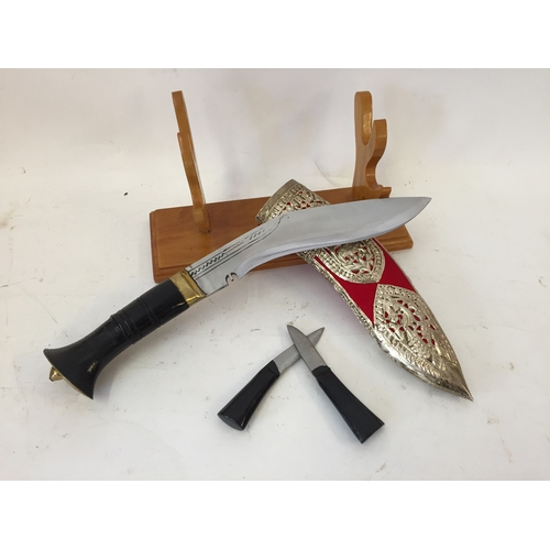 140 - Kothimoda Khukuri knife with a red velvet and silver coloured scabbard on wooden base