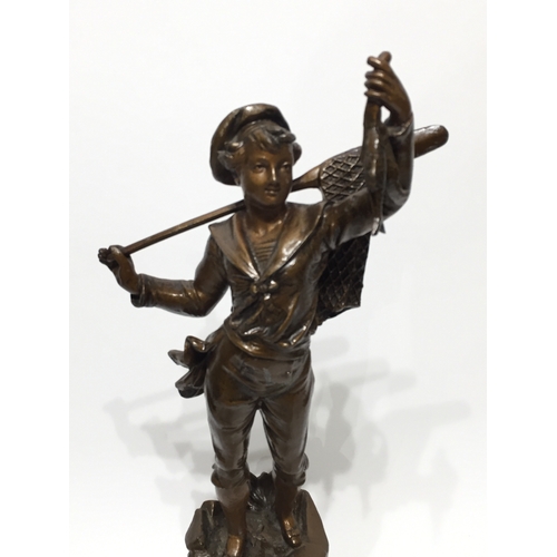 137 - Spelter statue 45cm tall a young boy carrying fish and a net