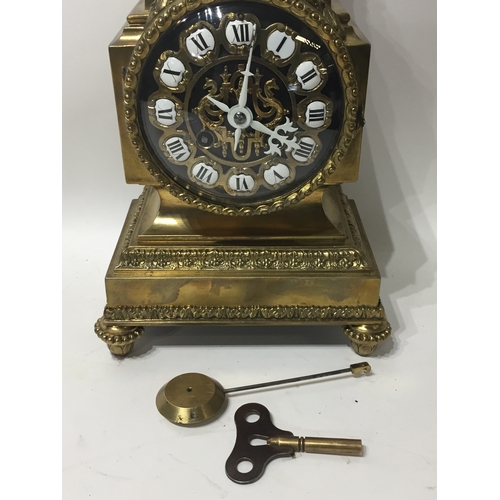 296 - Ormolu  Mantle Clock With Enamel Dials And A Floral Finial With Key And Pendulum. 29cms High