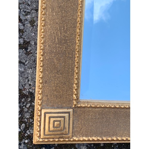 253 - Decorative Gilt Framed Aztec Style Bevelled Edge Mirror. 105 x 74 cms