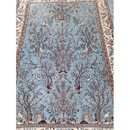 80 - Handmade Blue ground Rug with Stylised Tree of Life motif to centre. 205cm x 147cm