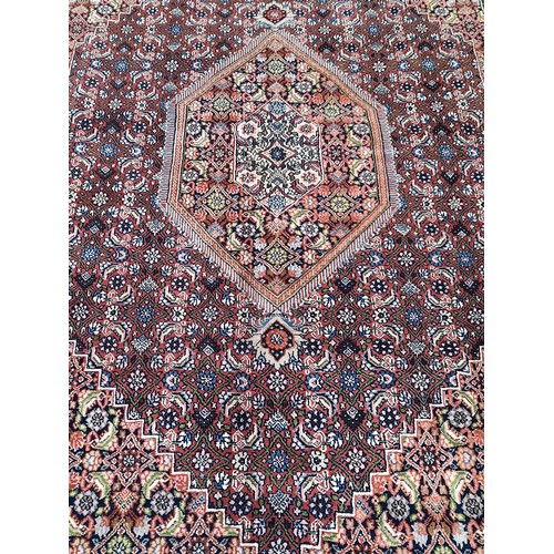 52 - Red ground hand knotted Rug with multi colour Lozenge to centre, 243cm x 170cm