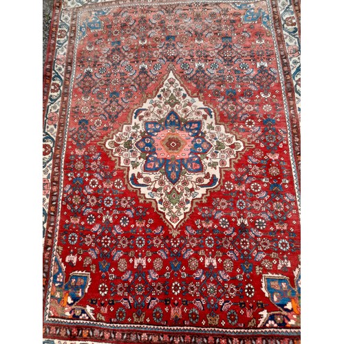 95 - Hand Knotted Red ground Rug with Diamond Centre, 165cm x 115cm