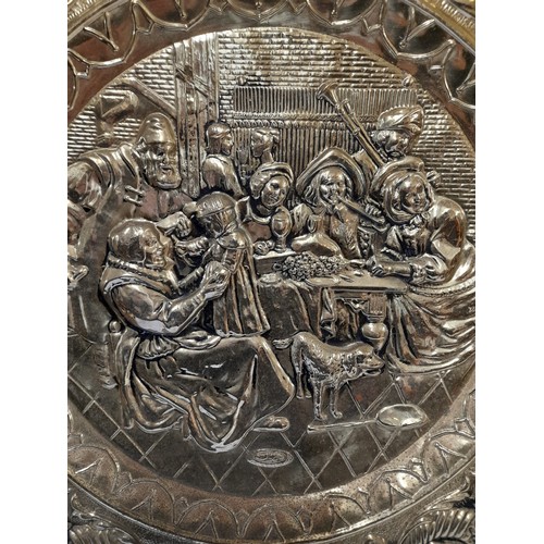 35 - Large Brass Wall hanging embossed Plate showing a Group of people around a table eating, drinking an... 