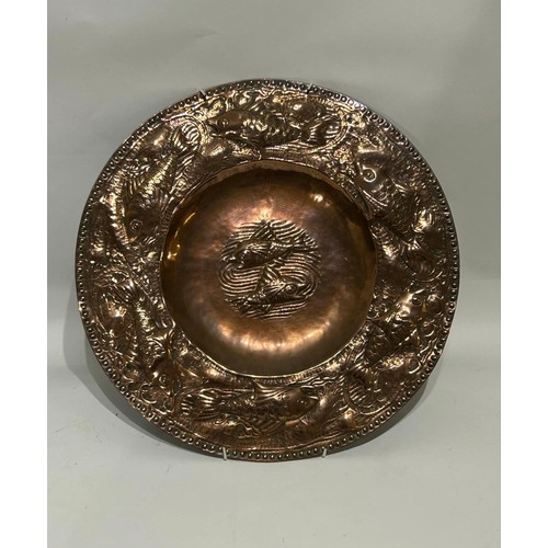 34 - Hammered copper plate in the style of arts and crafts with fish decoration. Measures 31.5 cm Diam