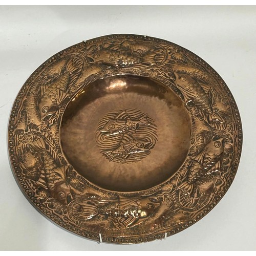 34 - Hammered copper plate in the style of arts and crafts with fish decoration. Measures 31.5 cm Diam