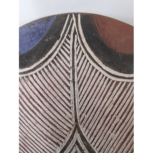 199 - Tribal Carved wood oval Shield with carved decoration finished in white, blue and red, 30cm x 27cm