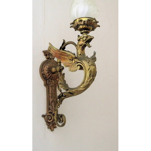 174 - Pair of ornate brass wall lights with winged serpent decoration, shaped shades, on backplates