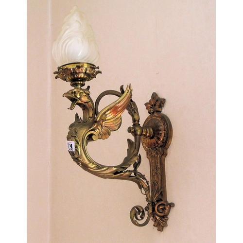 174 - Pair of ornate brass wall lights with winged serpent decoration, shaped shades, on backplates