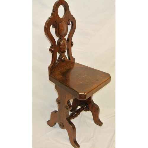 345 - Oak hall chair with shield shaped pierced back, angled sides, on plinths with turned stretcher