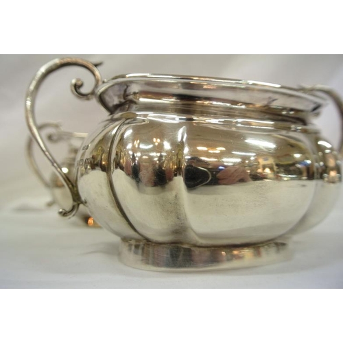 142 - Birmingham silver sugar bowl and cream jug of oval panelled form, with shaped scroll handles, dated ... 