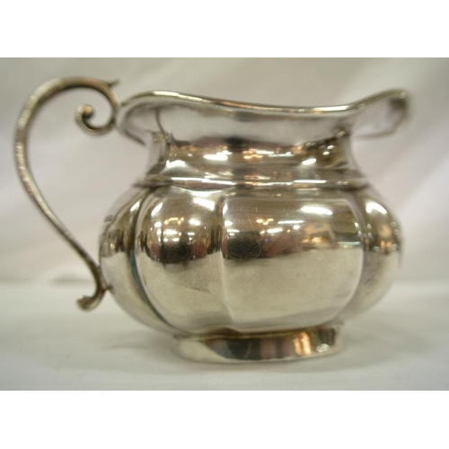 142 - Birmingham silver sugar bowl and cream jug of oval panelled form, with shaped scroll handles, dated ... 