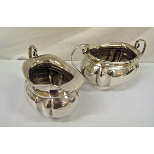 142 - Birmingham silver sugar bowl and cream jug of oval panelled form, with shaped scroll handles, dated ... 