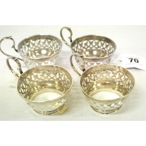 70 - Set of four Birmingham silver round cup holders with pierced decoration and shaped handles, dated 19... 