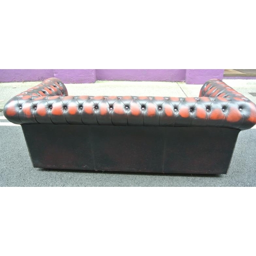 271 - Leather upholstered three seater Chesterfield couch with buttoned upholstery, on castors