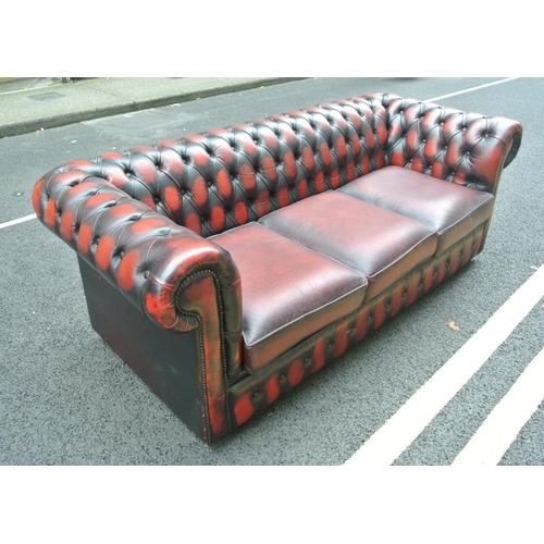 271 - Leather upholstered three seater Chesterfield couch with buttoned upholstery, on castors