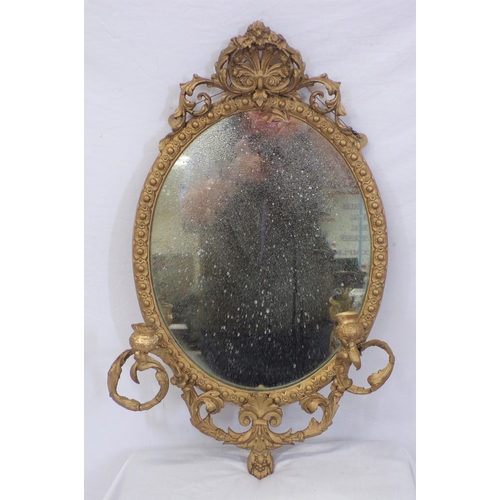 223 - Victorian gilt framed oval wall mirror with foliate decoration and sconces