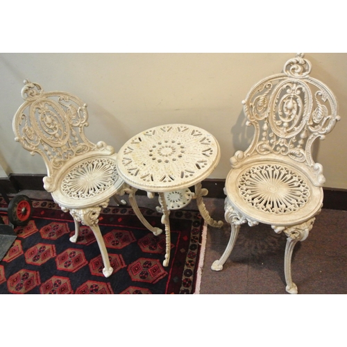 157 - Three piece cast iron garden or patio set, round table and pair of chairs with ornate scroll decorat... 