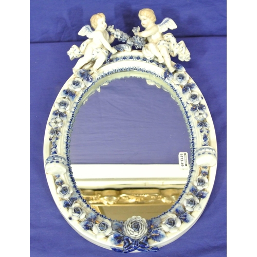167 - Oval Dresden style porcelain framed mirror with ornate cherub and foliate encrustation