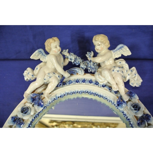 167 - Oval Dresden style porcelain framed mirror with ornate cherub and foliate encrustation